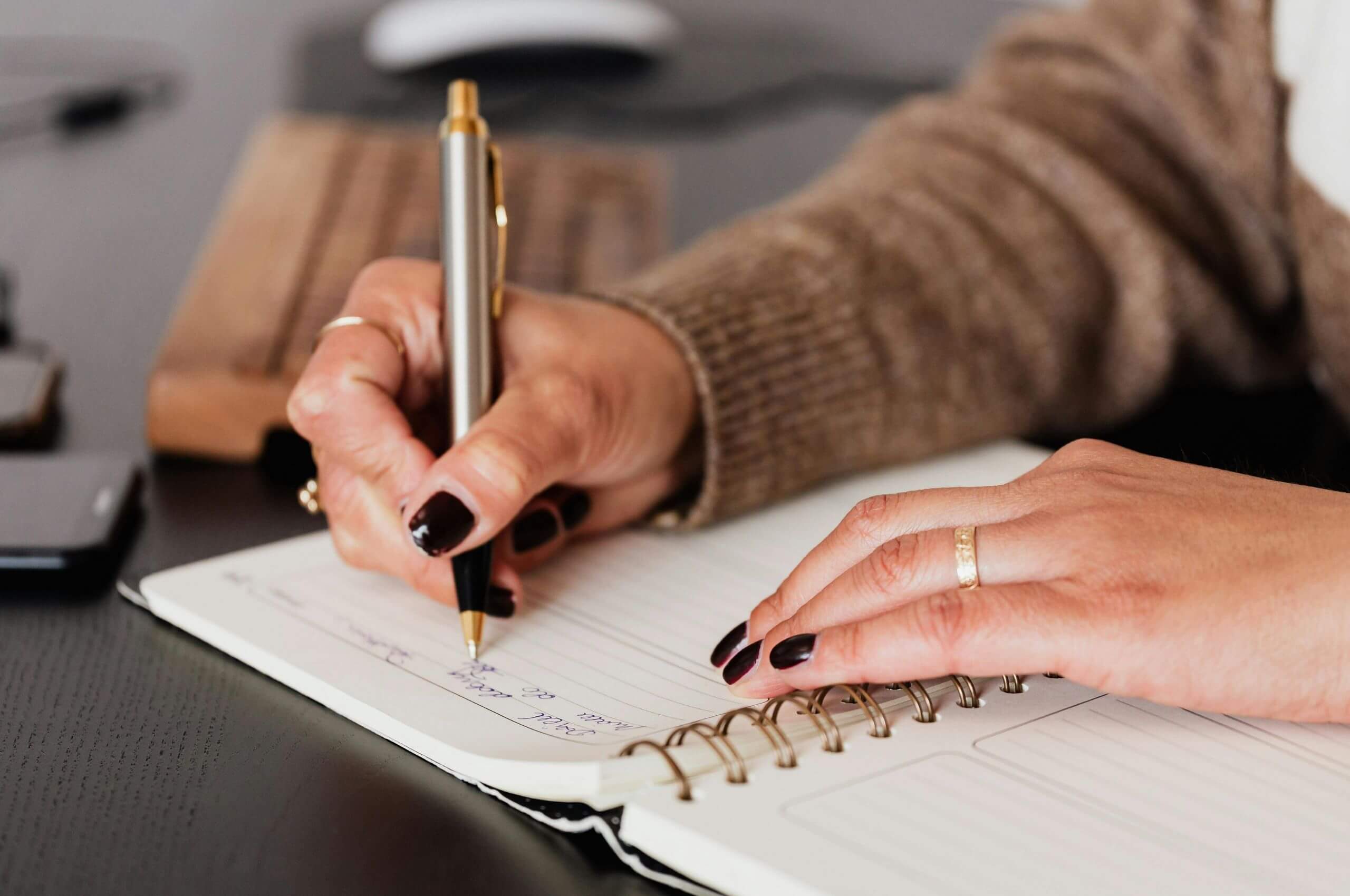 A female with black nails writing content on paper